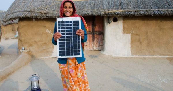investimento recorde em energia renovável - mulher com painel solar na Índia